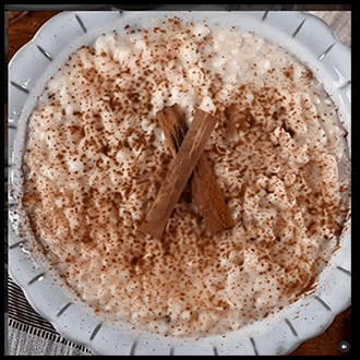 Creamy three-milk rice pudding served in a dish and dusted with ground cinnamon